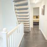 Hausgang mit Treppe und Blick in Schlafzimmer und Bad.