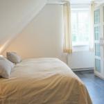 Schlafzimmer mit Dachschrägen, Bett, Fenster und Schrank.