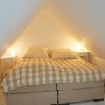 Schlafzimmer mit Doppelbett, zwei Nachttischen und schrägen Wänden.