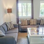 Ein Wohnzimmer mit zwei grauen Sofas, einem weißen Couchtisch und zwei Fenstern.