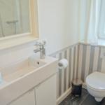 Badezimmer mit Waschbecken, Spiegel, Toilette und Fenster