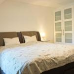 Schlafzimmer mit Doppelbett, Nachttisch und Schrank unter Dachschrägen.