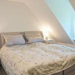 Schlafzimmer mit Dachschrägen, Bett, zwei Nachttischen und Fenster.