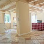 Küche mit Essbereich und Wohnzimmer mit rotem Sofa und Holzbalkendecke.