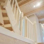 Haus mit Holzdecke, weißer Treppe und Segelschiffmodell.