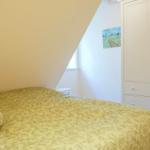 Schlafzimmer mit Bett, Kleiderschrank und Wandbild.