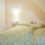 Schlafzimmer mit Doppelbett, Nachttisch und Lampe unter schräger Decke.