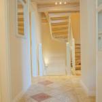 Flur mit Fliesenboden, Treppe und Schrank mit Glasfront.