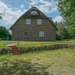 Ein zweistöckiges Haus mit strohgedecktem Dach und Steinmauer im Gras.