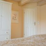 Schlafzimmer mit weißem Schrank, Bett und Holzbalken an der Decke.