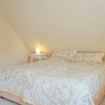 Schlafzimmer mit Doppelbett, zwei Nachttischen und angrenzender Badewanne.