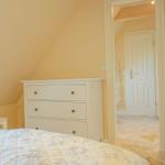 Schlafzimmer mit Bett, Schrank und Tür zum Flur.