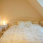 Schlafzimmer mit Bett, Nachttischen und Wandbild unter Dachschrägen.