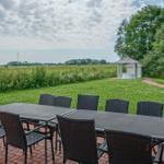 Terrasse mit Tisch und Stühlen, Blick auf Grasfläche und Pavillon.