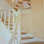 Treppenhaus mit weißer Balustrade und Holzstufen, Schiffmodell an der Decke.