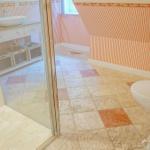Badezimmer mit Toilette, Dusche und Waschbecken. Wandtapete mit Streifenmuster.