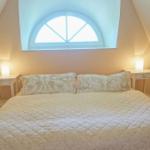 Schlafzimmer mit Dachschrägen, Bett, zwei Nachttischen und Fenster