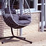 Eierschalen-Schaukelstuhl mit Kissen auf Terrasse vor Hauswand