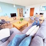 Wohn- und Essbereich mit Sofa, Esstisch und Fernseher.