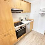 Küche mit Holzschränken, Spüle, Kühlschrank und Kochfeld.