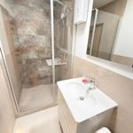 Badezimmer mit Dusche, Waschbecken und Spiegel