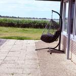 Hängesessel auf Terrasse mit Blick auf Gras und Wasser.