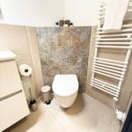 Badezimmer mit Toilette, Heizkörper und Mosaikwand