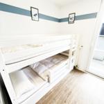 Zimmer mit Doppelstockbett, Holzboden und Fenster zur Terrasse.