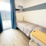 Ein Schlafzimmer mit Bett, blauen Vorhängen und Holzboden. An der Wand hängt ein Bild.