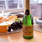 Auf dem Tisch steht eine Sektflasche neben Käse und Trauben.