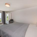 Schlafzimmer mit Doppelbett, Schrank und Blick auf Außenbereich.
