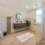 Badezimmer mit Dusche, Waschbecken und Toilette. Boden- und Wandfliesen.