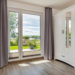 Zimmer mit Blick auf Hafen, weißer Schrank und graue Vorhänge.