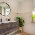 Bad mit Waschbecken, Spiegel und Pflanzen an Fensterbank.