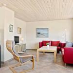 Wohnzimmer mit rotem Sofa, Holztisch und Kaminofen. Decke aus Holz, Wandbild und Fenster.
