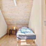 Ein Schlafzimmer mit Dachschräge, Holzboden und einem Bett mit blauer Bettwäsche.