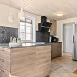 Moderne Küche mit Holzoberflächen, Edelstahlkühlschrank und Mosaikrückwand.