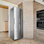 Küche mit Edelstahl-Kühlschrank und eingebauten Backofen und Mikrowelle.