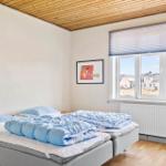 Schlafzimmer mit Doppelbett, Holzboden und Fenster mit Blick auf Außenbereich.