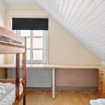 Zimmer mit Doppelstockbett, Schreibtisch und Schrank unter schrägem Dach