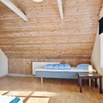 Schlafzimmer mit Holzdecke, Bett und Tisch. Fenster mit Jalousie.
