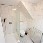 Badezimmer mit Dusche, WC und Heizkörper an der Wand.