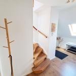 Holztreppe führt nach oben. Wandhaken und Fenster sind sichtbar.