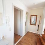 Eingangsbereich mit Holzboden, Spiegel, Kleiderständer und Treppe.