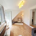 Wohnzimmer mit Holzboden, Fenster, Sessel und Lampen.