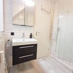 Badezimmer mit Waschbecken, Spiegel und Dusche.