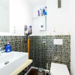 Badezimmer mit Waschbecken, Toilette und Mosaikwand