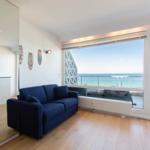 Ein Wohnzimmer mit blauem Sofa und Blick auf das Meer.