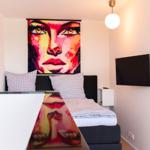 Schlafzimmer mit Bett, Wandbild und Fernseher an der Wand.