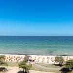 Strand mit Sandkästen und blauem Meer unter klarem Himmel.